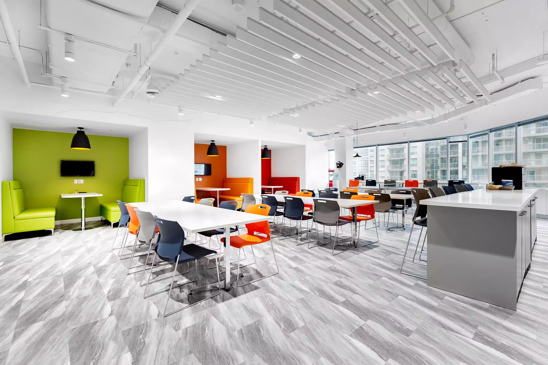 Modern office break room in the banking industry with colorful furniture, green and orange accents, and large windows.