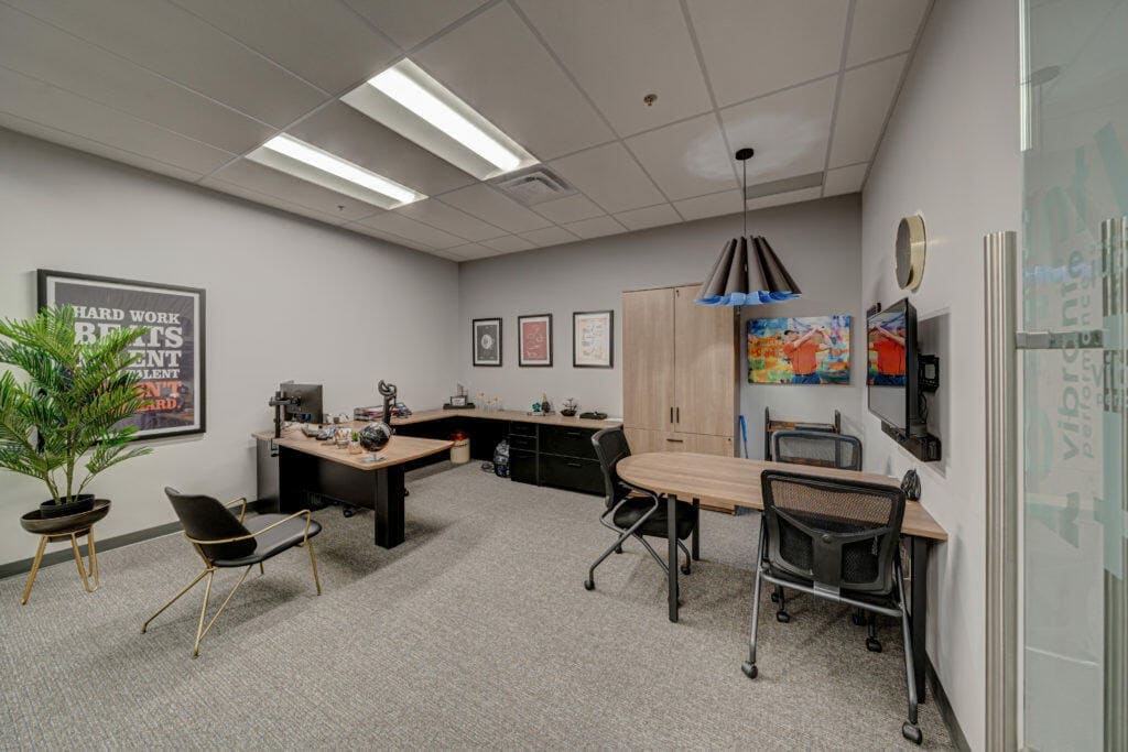 An image of a private office with desks, plant, and artwork
