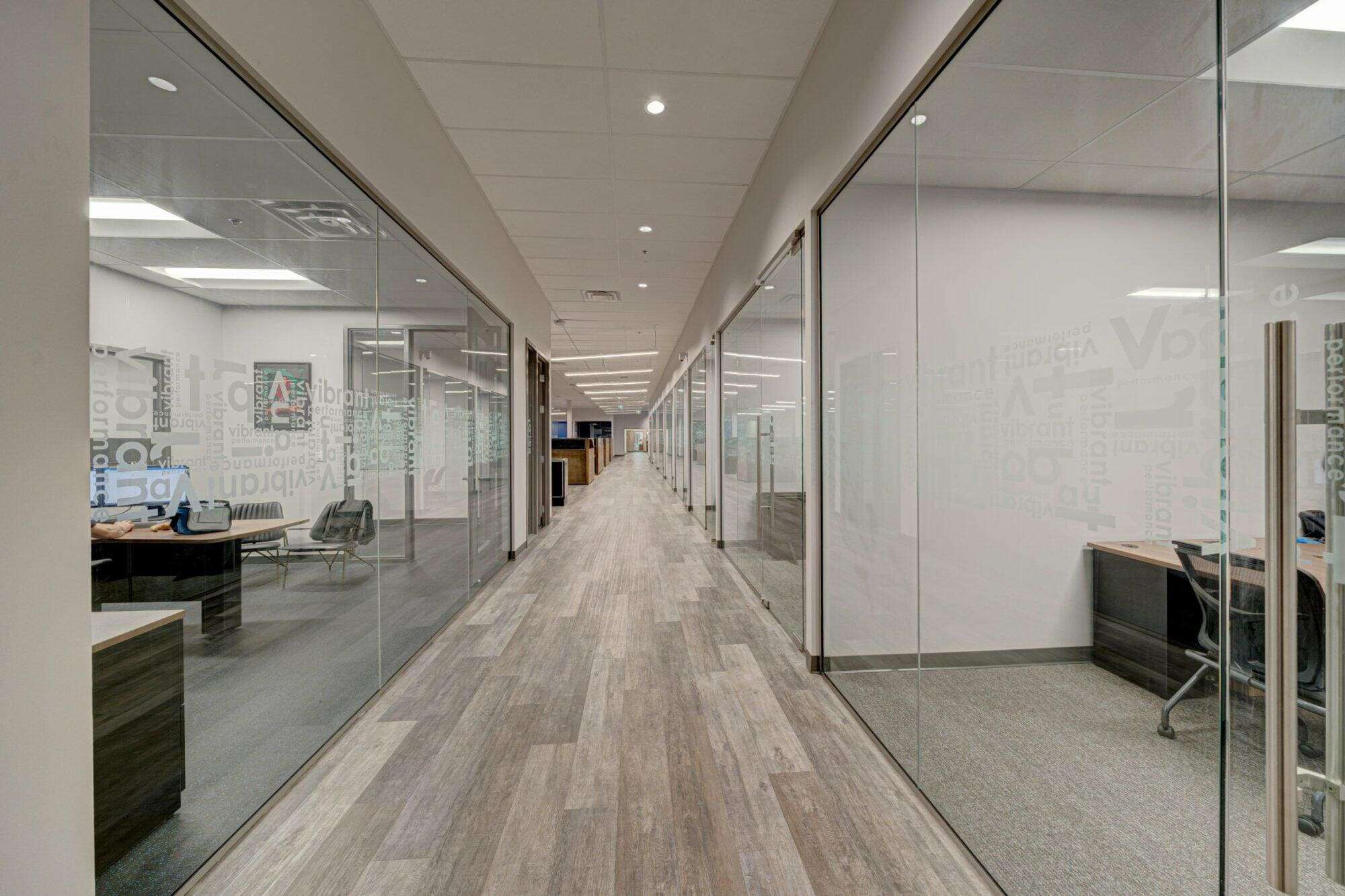 An image of a hallway with grey wood flooring and glass walls