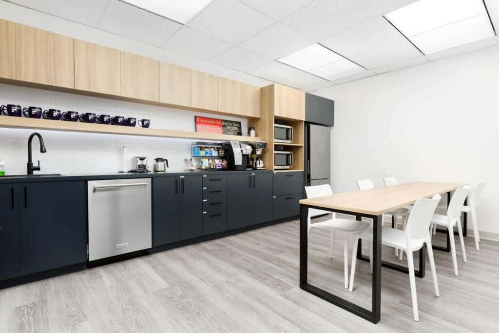 Modern business lunchroom with stainless steel appliances and light wood and black cabinetry