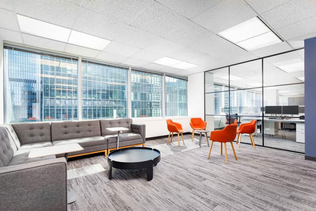 Well-lit lounge area with large windows, modern sectional sofa and upholstered accent chairs