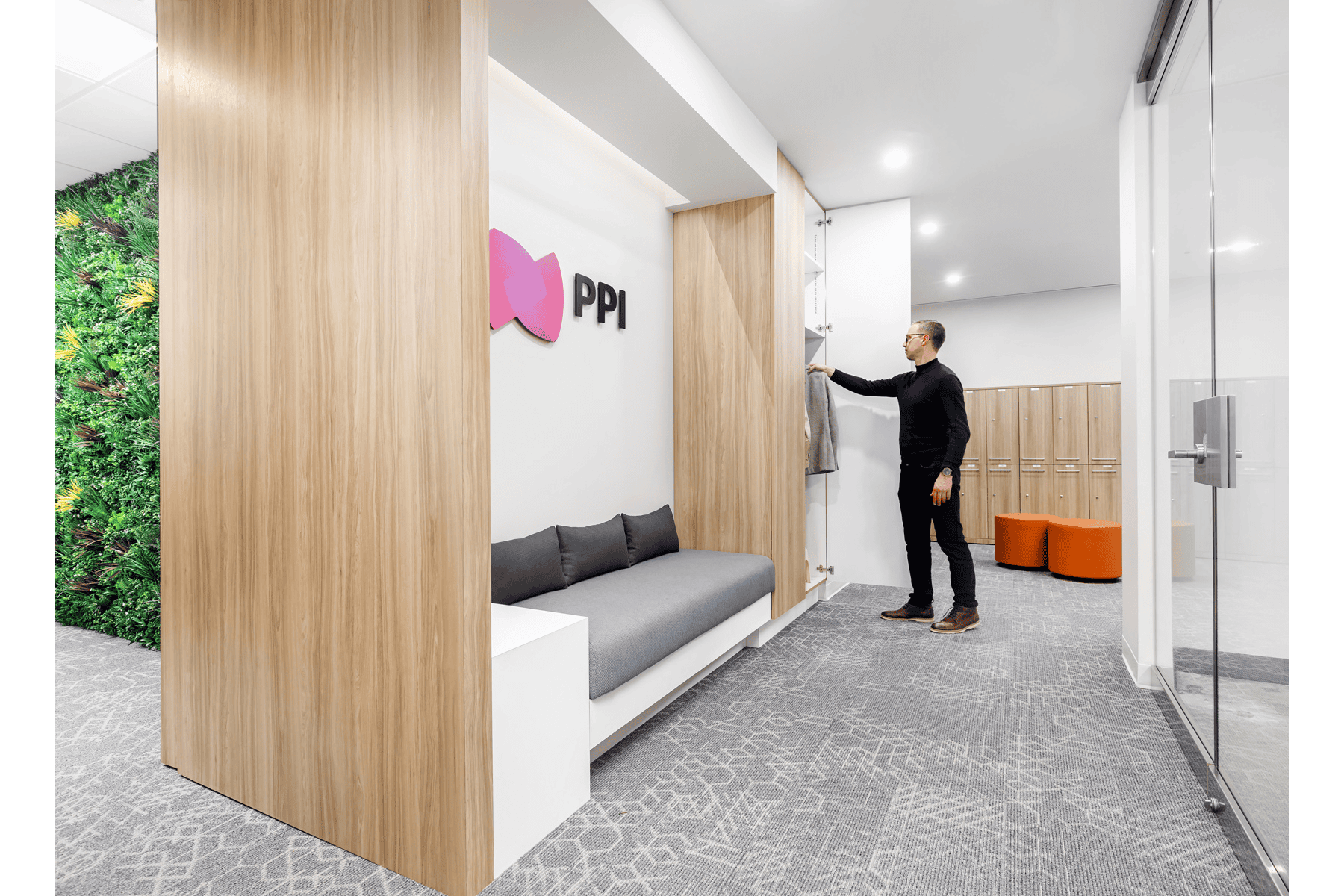 A man in business attire adjusting a whiteboard in a modern office lobby with wooden accents and a green wall.