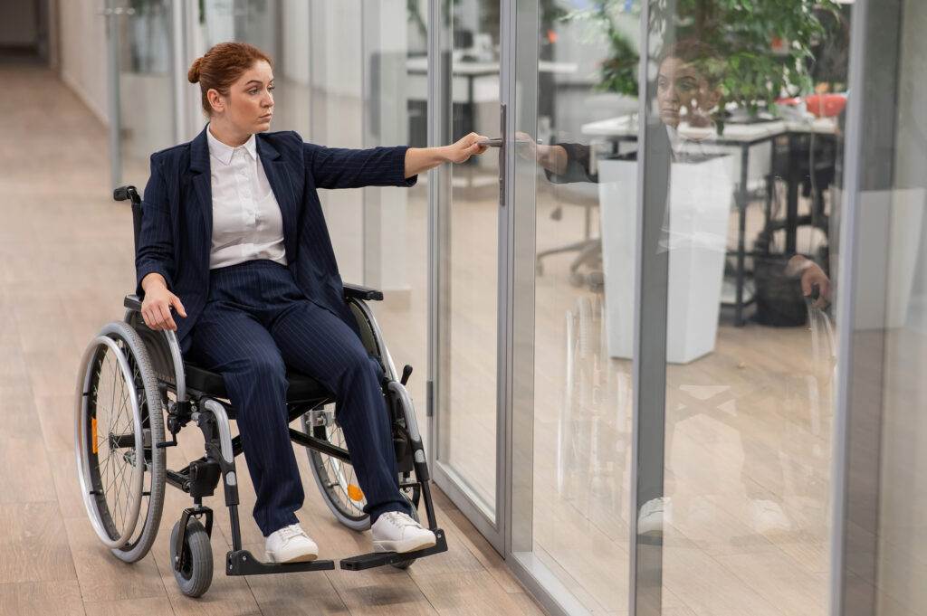 Red-haired caucasian woman in a wheelchair trying to open the door in the office