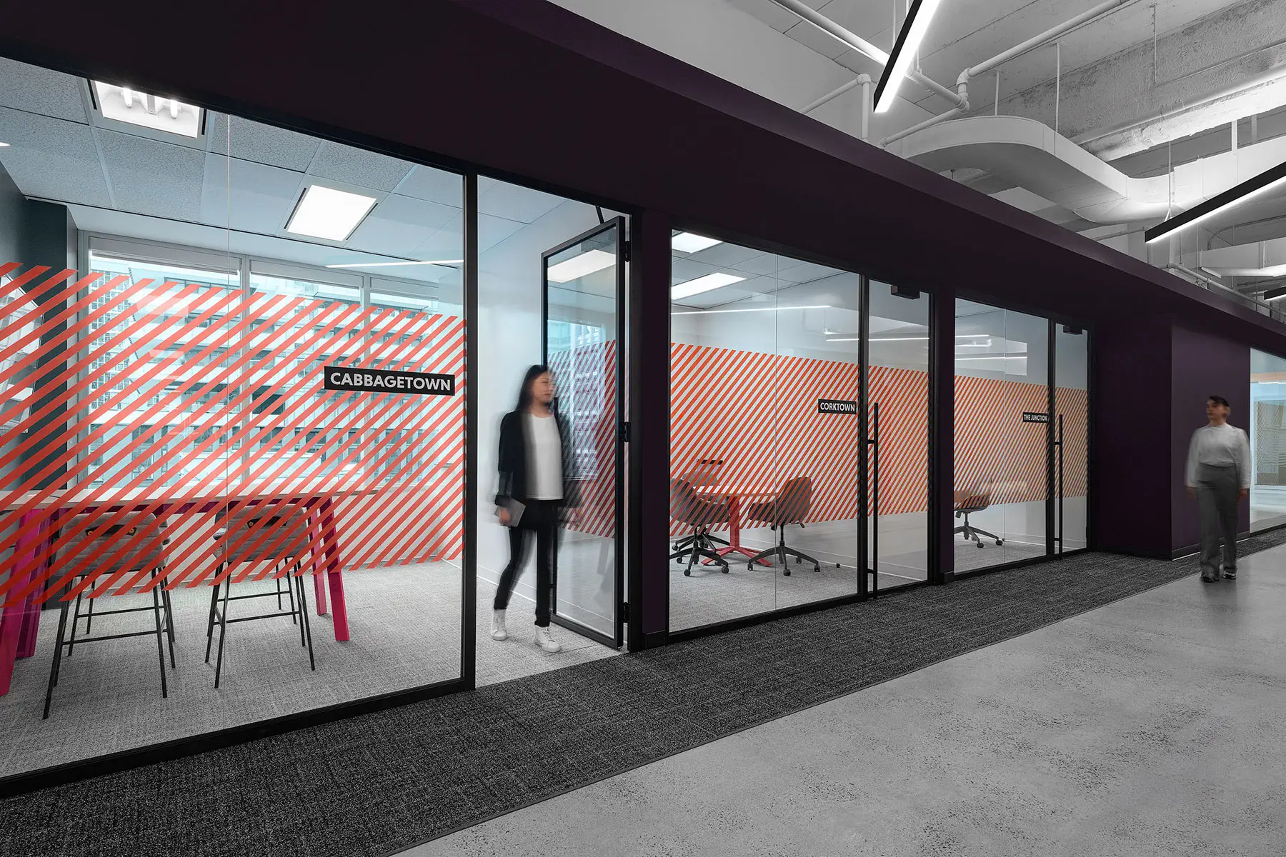 Two people walking in an office hallway with glass-walled meeting rooms named "Cabbagetown" and red diagonal striped patterns.