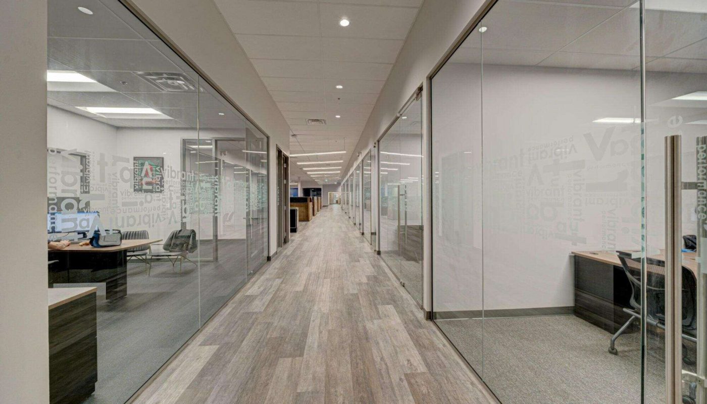 An image of a hallway with grey wood flooring and glass walls
