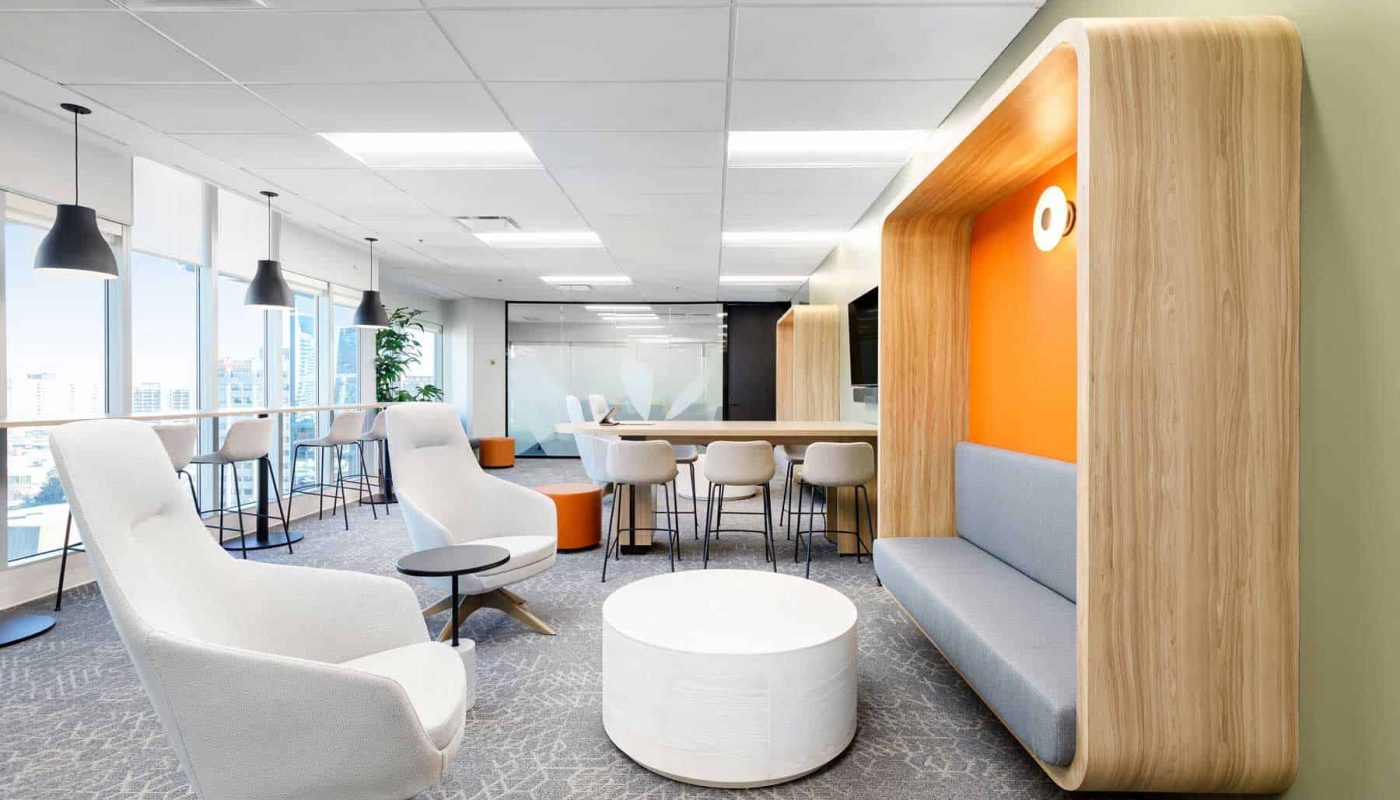 Modern office lounge with a variety of commercial office furniture, including couches, chairs, and bar stools, featuring bright interiors and large windows.